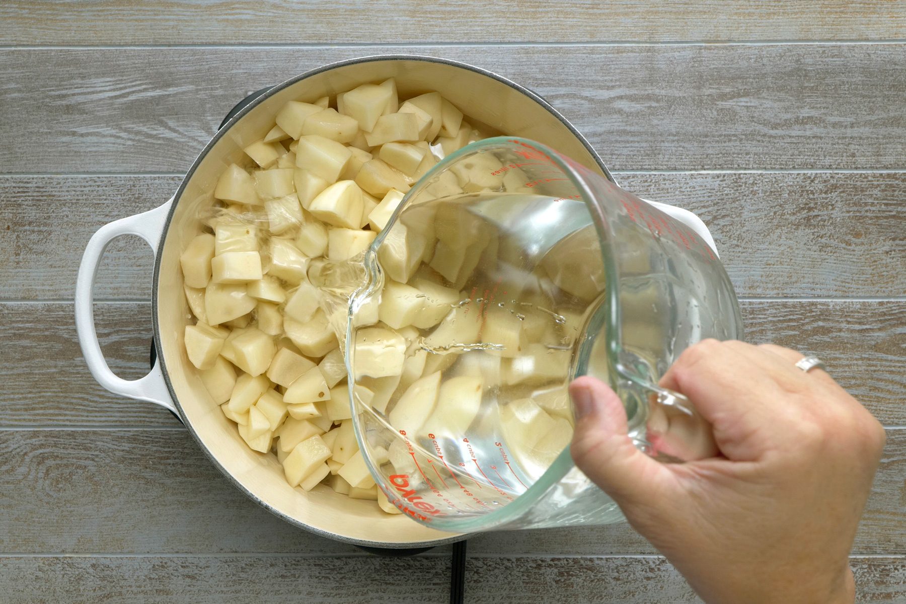 Pouring water to boil Potato cubes cut into pieces