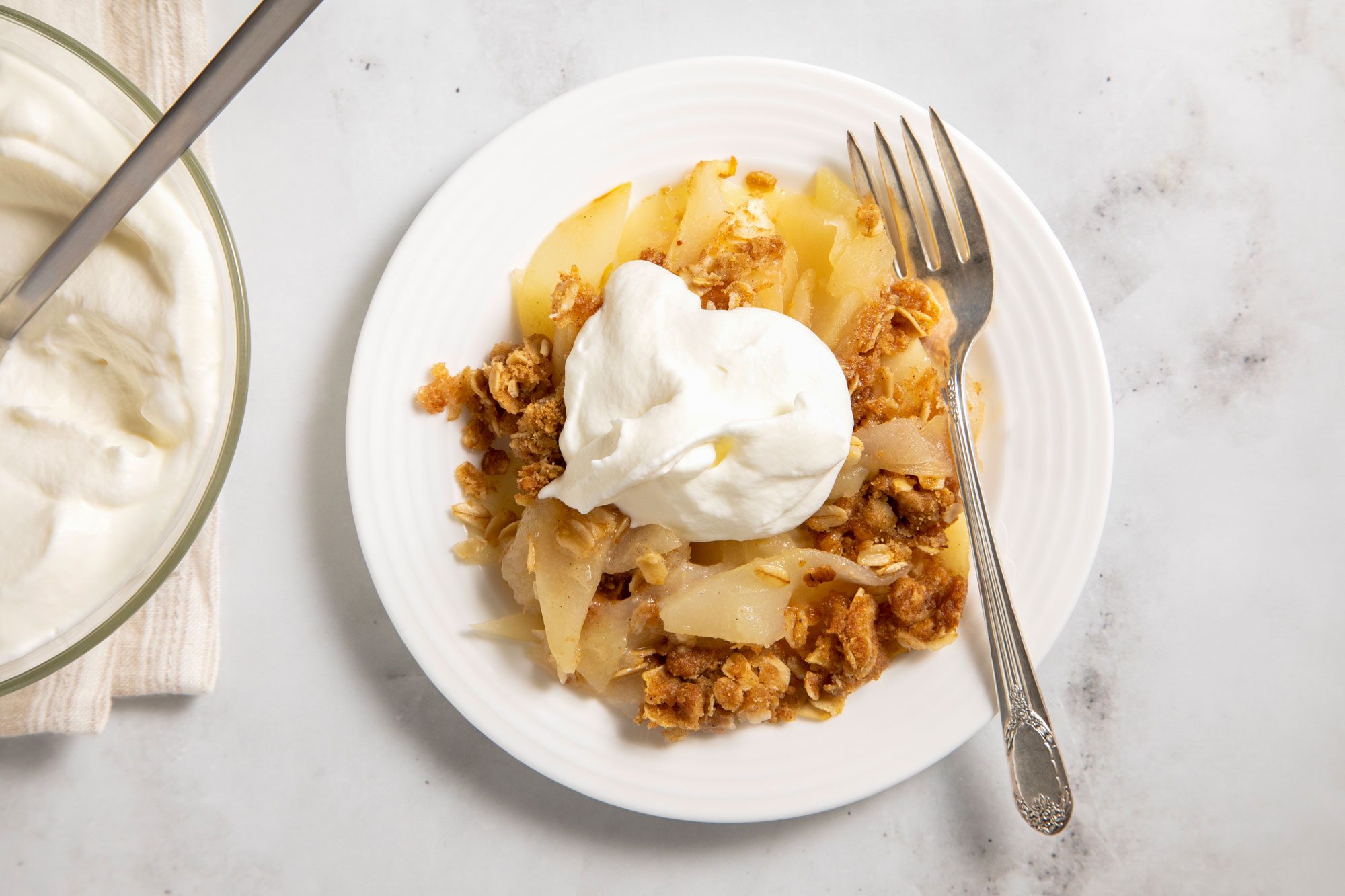 overhead shot; white background; Easy Apple-Pear Crisp served in a small white plate with silver fork;
