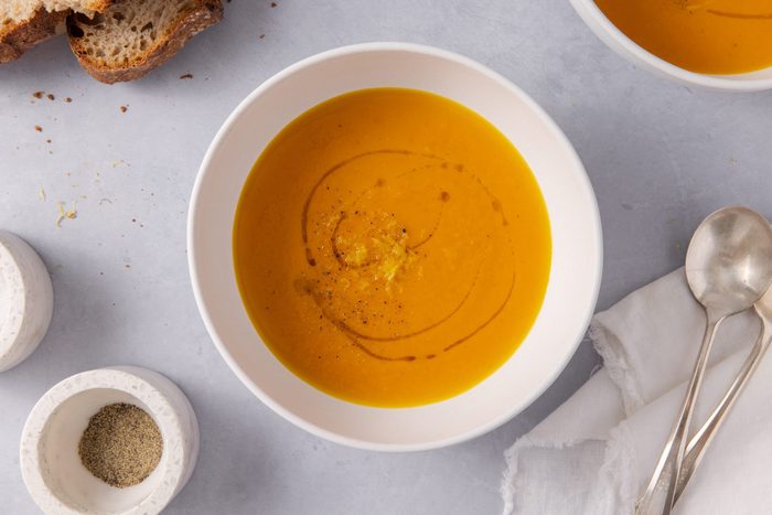 Soup served in a bowl with bread on the side.