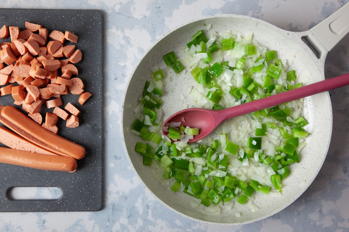 Step 2 of Taste of Home Chili Cheese Dog Casserole is cooking the onions, green peppers and celery in a pan