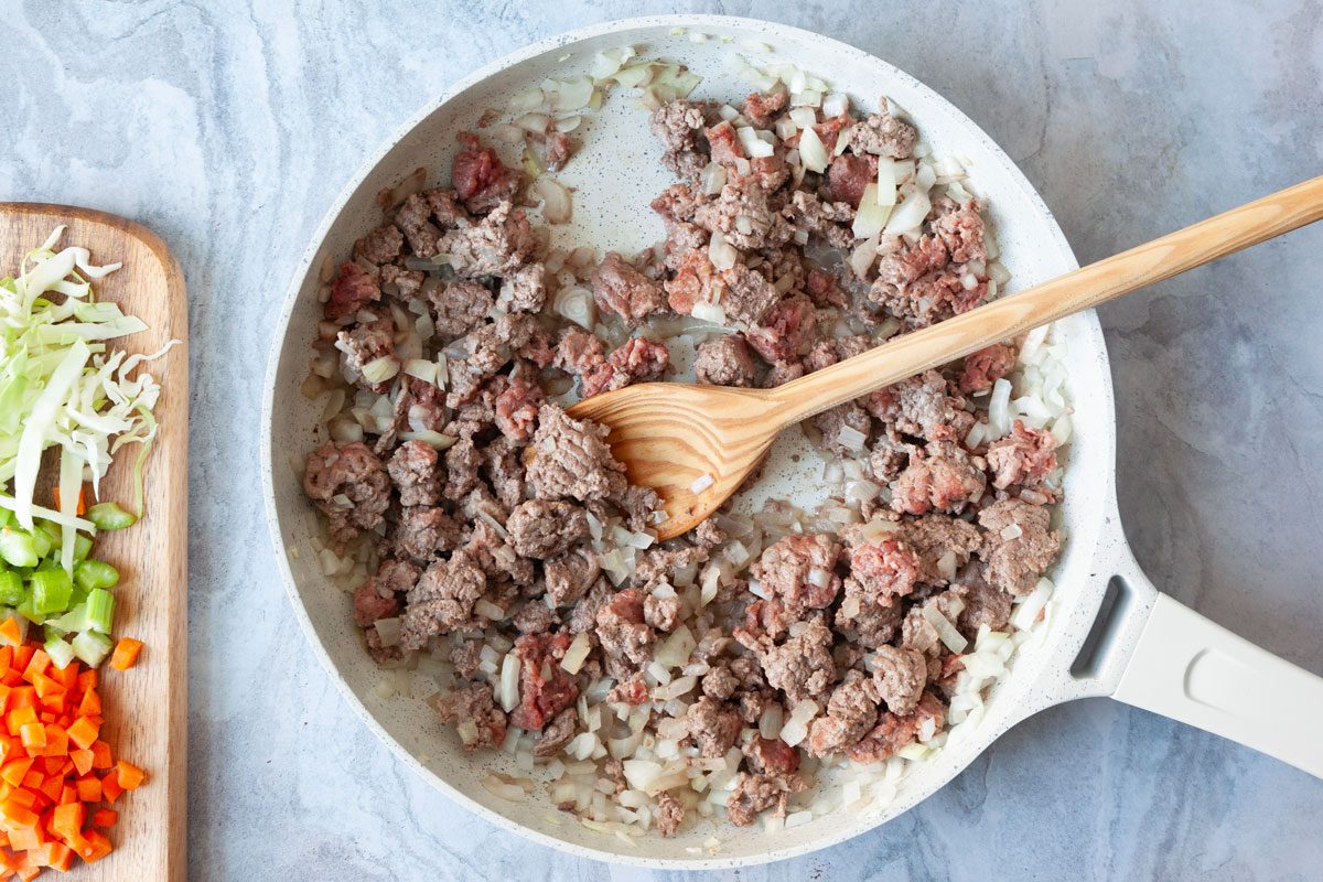 Step 1 of Taste of Home Crockpot Pasta Fagioli is browning ground beef and onion in a skillet