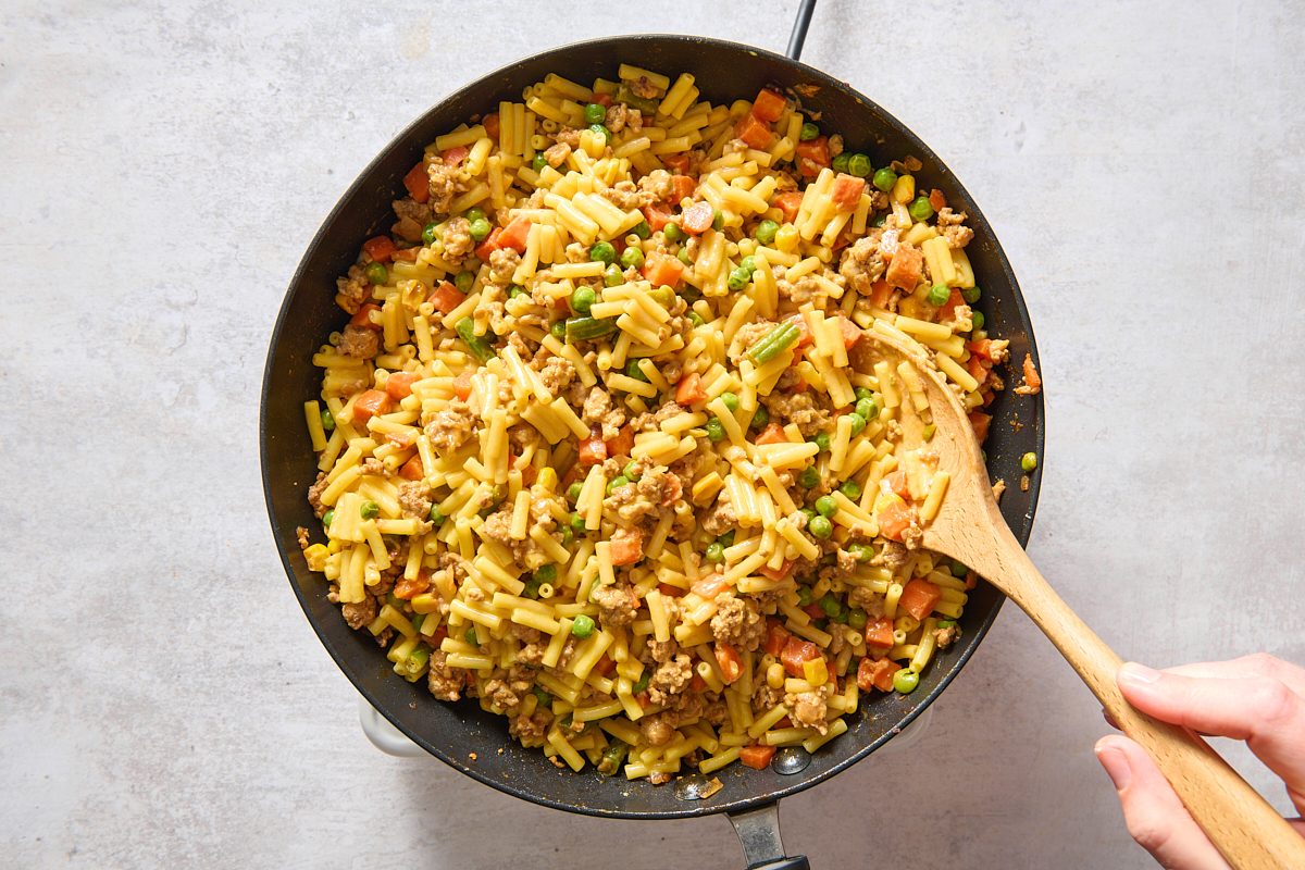 Stirring mac and cheese into the other ingredients in the skillet