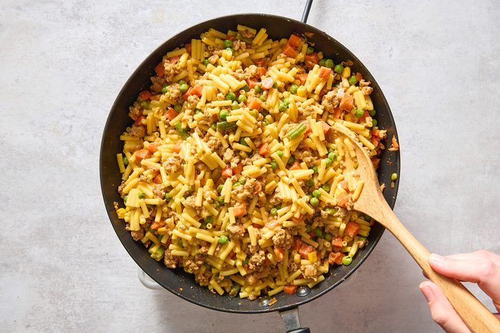 Stirring mac and cheese into the other ingredients in the skillet