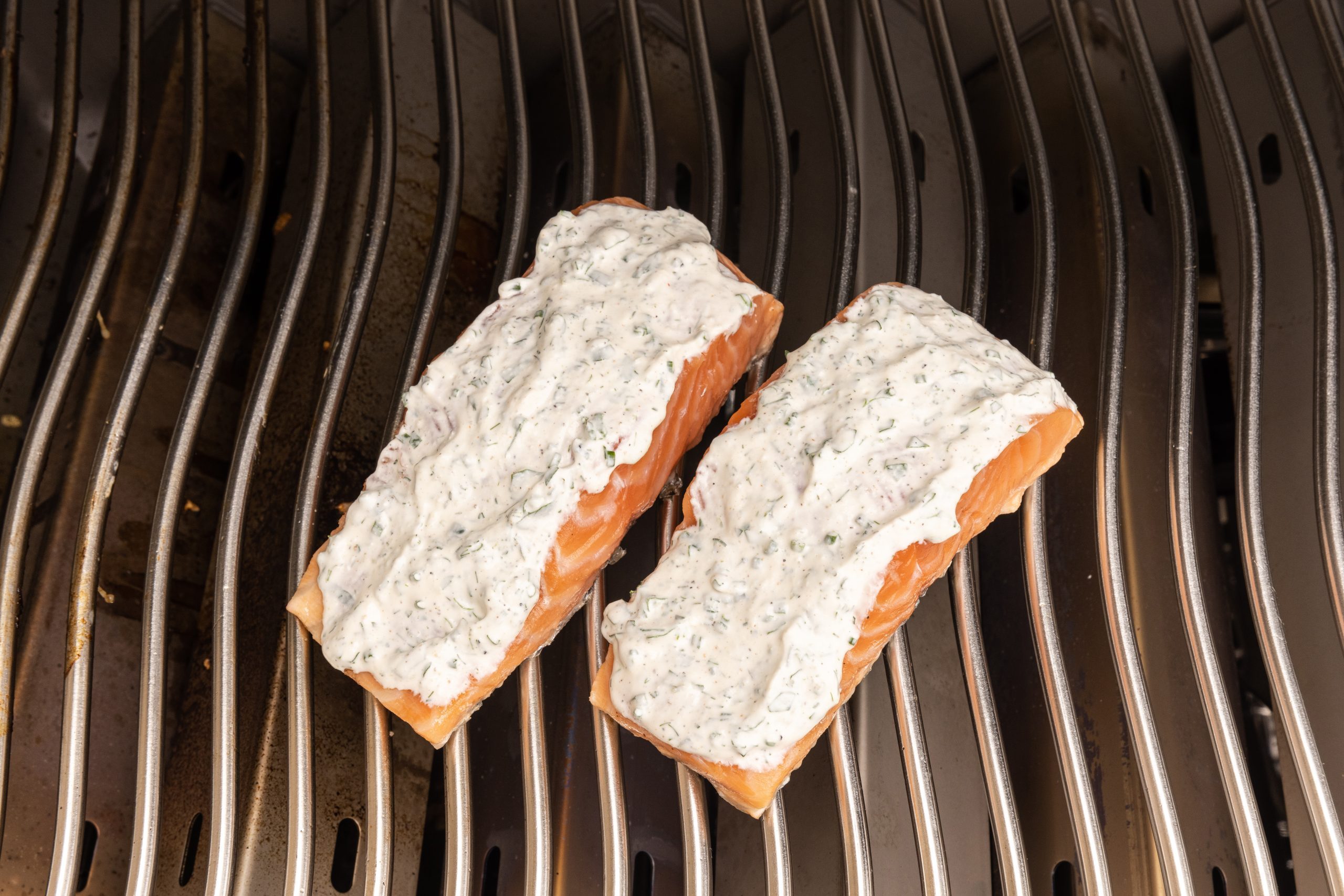 Salmon being grilled with dressing on top of it. 