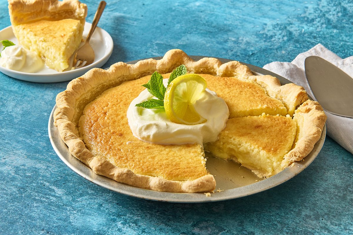 Lemon custard pie topped with whipped cream, lemon and mint