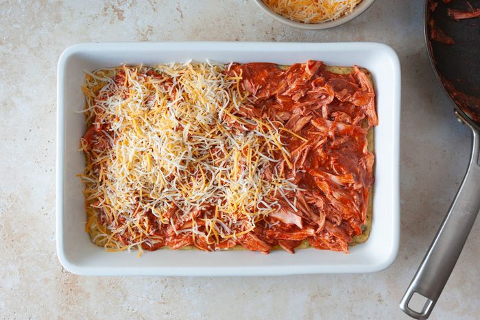 13x9 baking dish with cornbread mixture and topped with shredded chicken, tamale sauce and shredded cheese