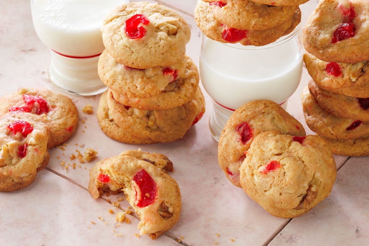 Cherry Cookies served with a glass of milk on a pink tile background
