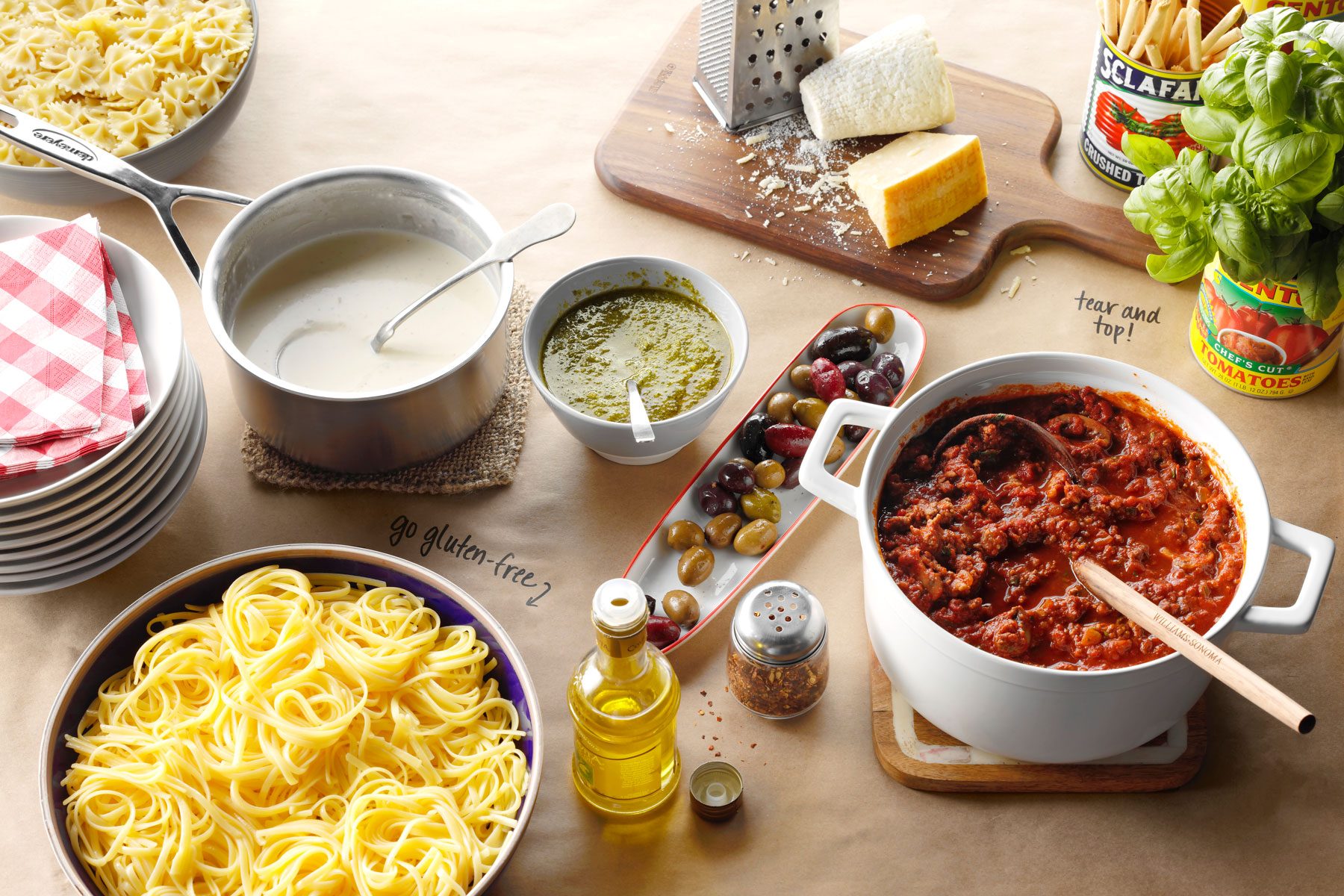 Large containers with Alfredo sauce, pasta and meatballs with oils, olives and cheeses.