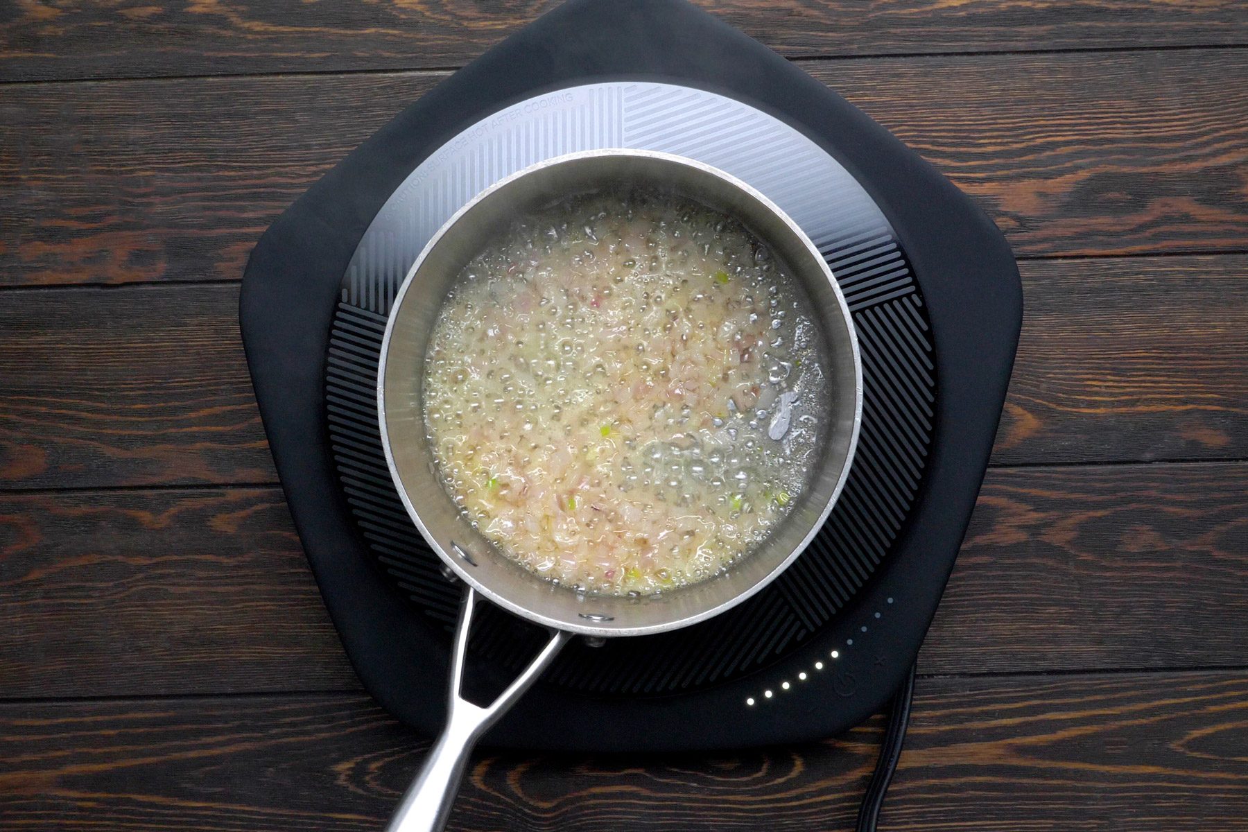 Garlic, shallots, and butter being heated in a large saucepan.