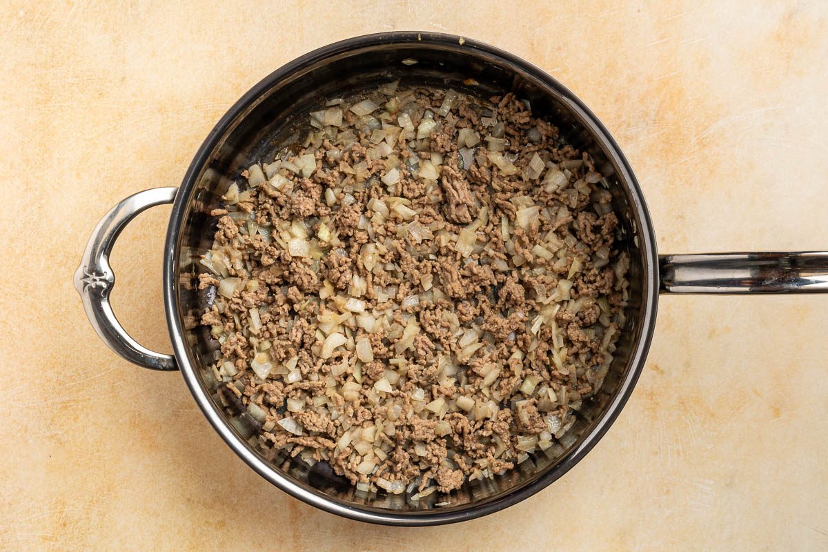 Taste of Home BBQ baked beans recipe photo of ground beef and onion cooked in a skillet.