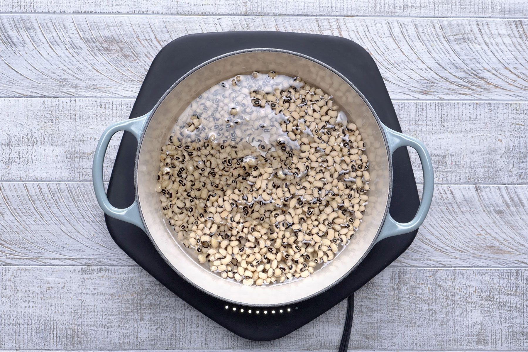 Peas soaked in a dutch oven on a textured background.