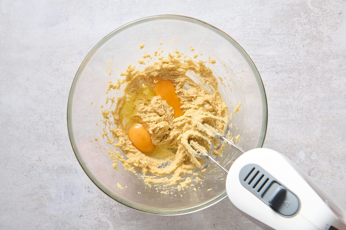 Beating eggs into the creamed mixture in a bowl