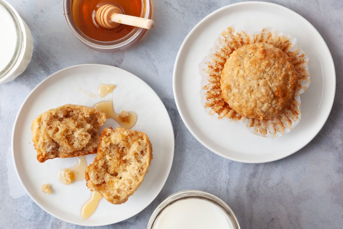 Single servings of Taste of Home Buttermilk Muffins on white plates, glasses of milk, honey