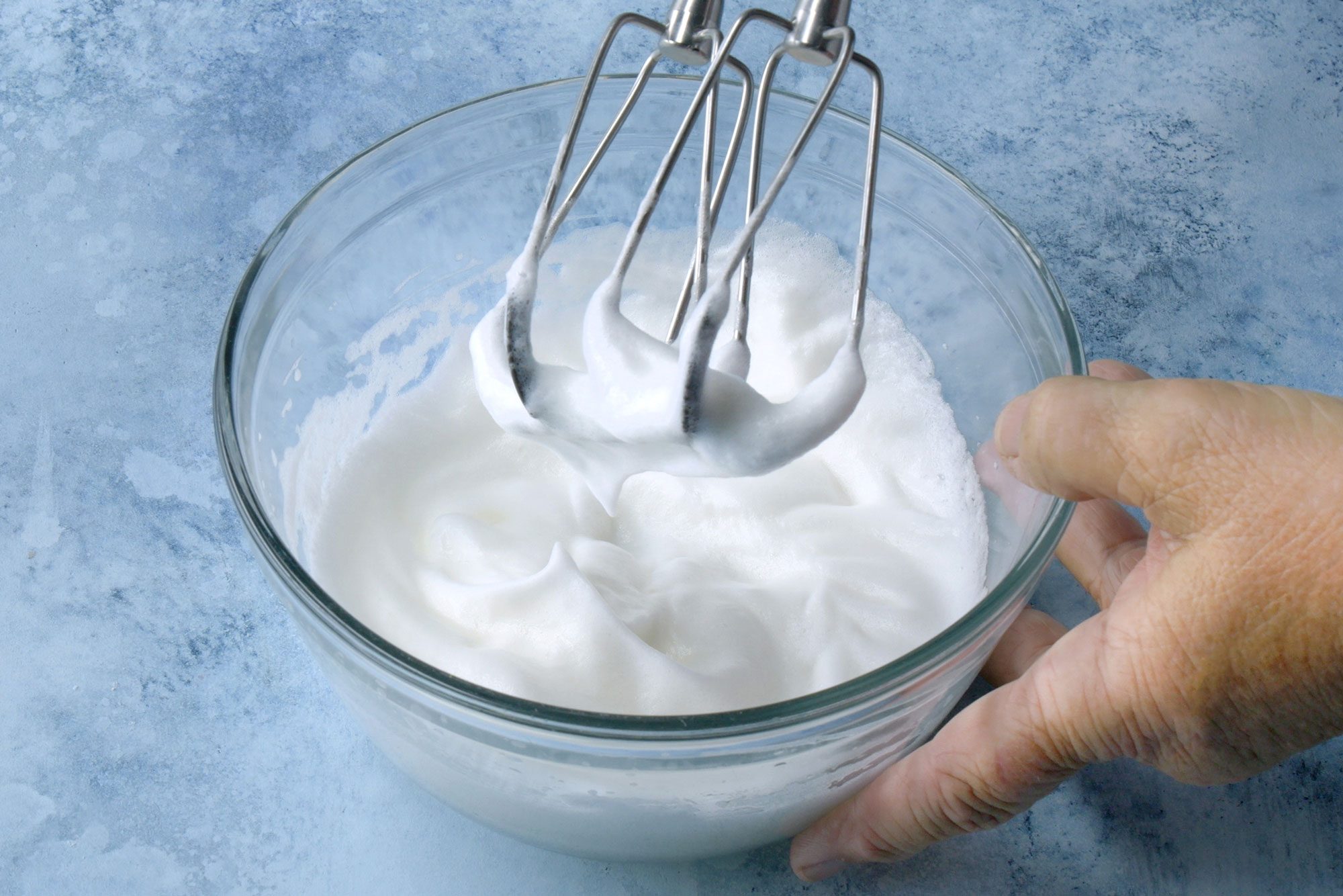 3/4th shot; light blue background; In a small bowl, beating egg whites until stiff peaks form;