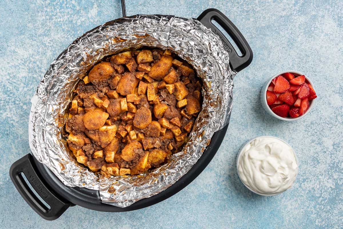 Taste of Home Donut Bread Pudding recipe photo the cooked bread pudding with sides of fresh berries and whipped cream.