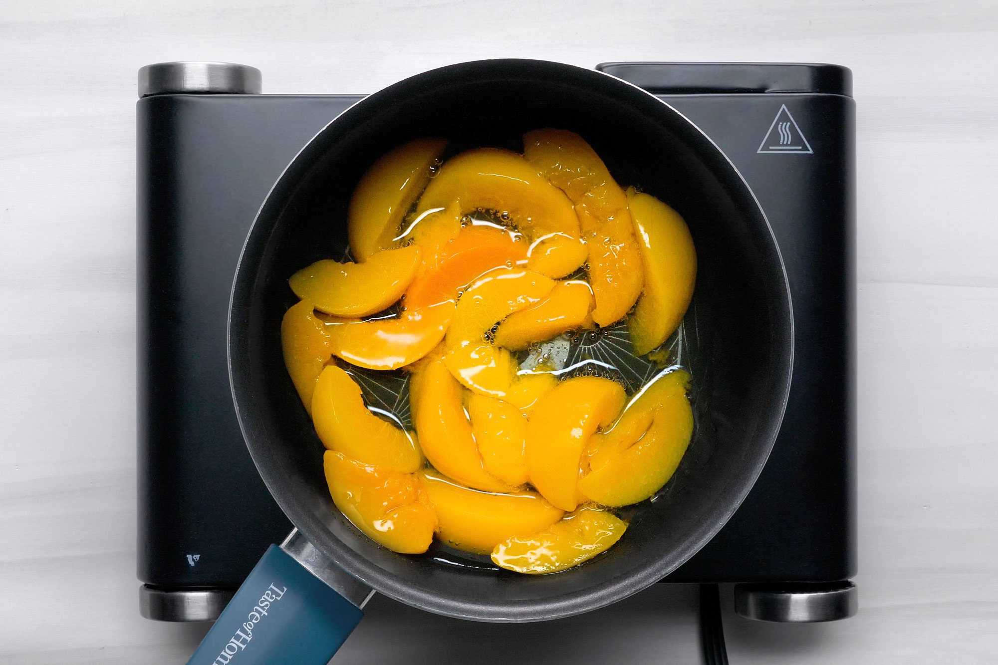 overhead shot; white background; In a saucepan, bringing peaches and reserved 1/4 cup juice just to a boil;