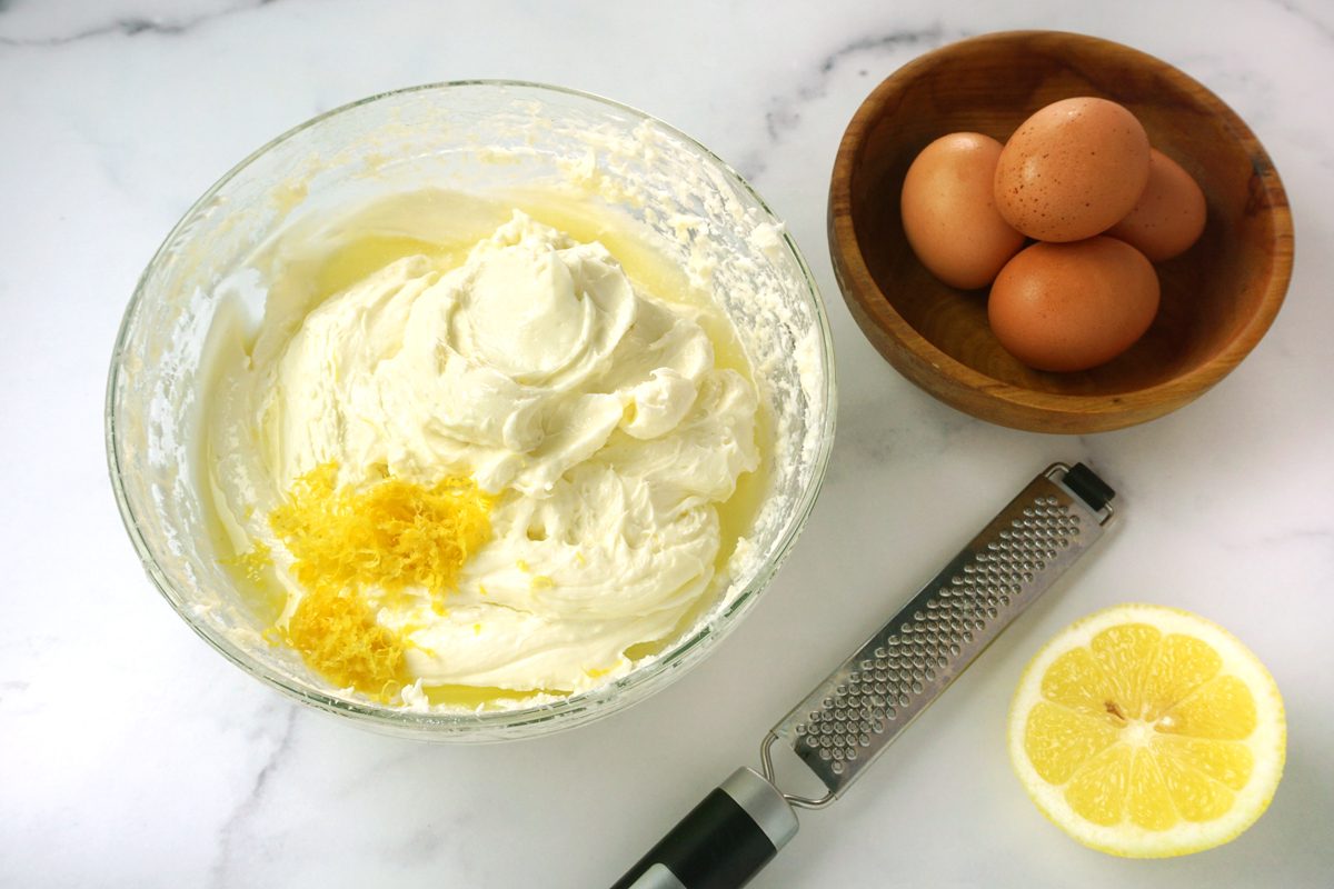 A bowl of beated cream cheese with lemon zest and eggs for lemon cheesecake bars for Taste of Home RMS 15811