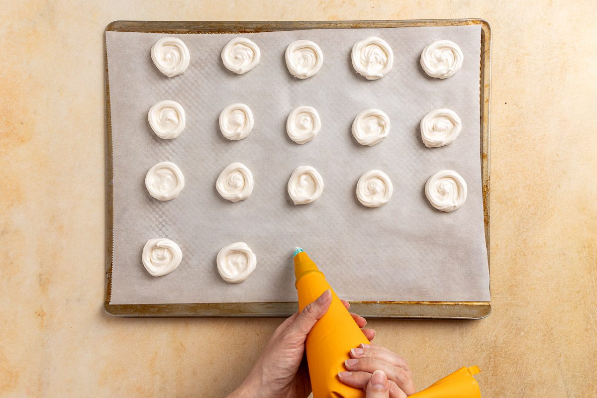 Taste of Home Lemon Meringue Cookies recipe photo of piping the meringue on a parchment paper covered cookie sheet.