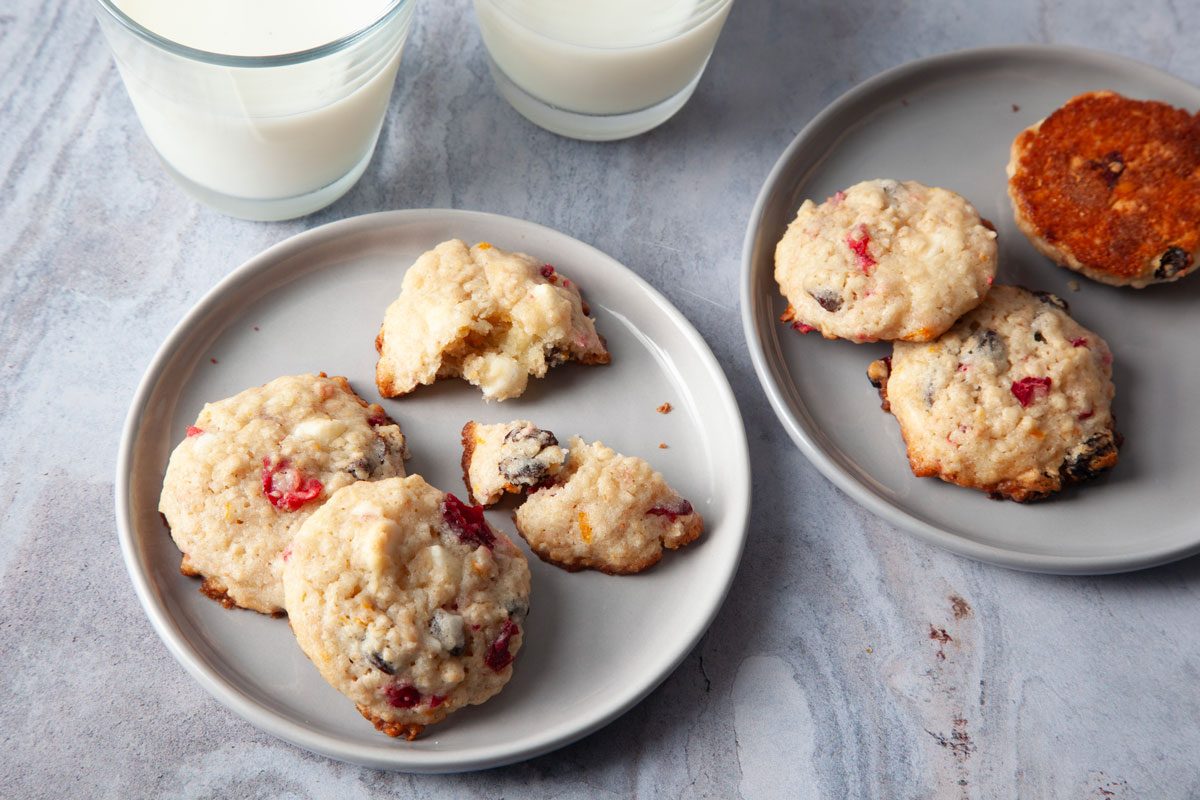 Close up of Taste of Home Oatmeal Cranberry Cookies on small plates with glasses of milk peaking in