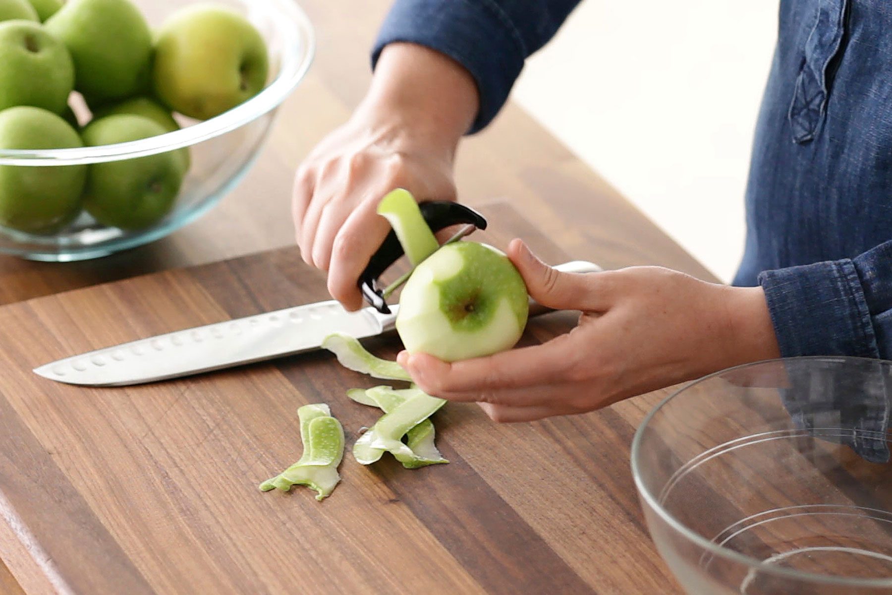 Person peeling a green apple