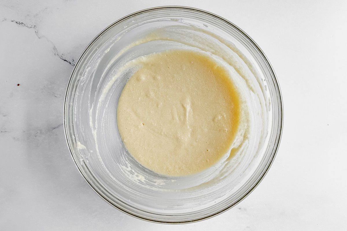 Ingredients for Taste of Home peach muffins in a glass bowl on a marble surface.