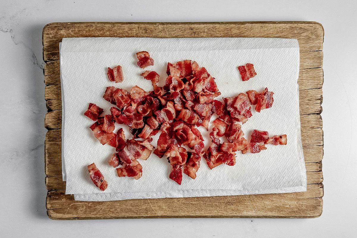 Cooked bacon on paper towels on a wooden board on a marble surface for Taste of Home tortellini carbonara.