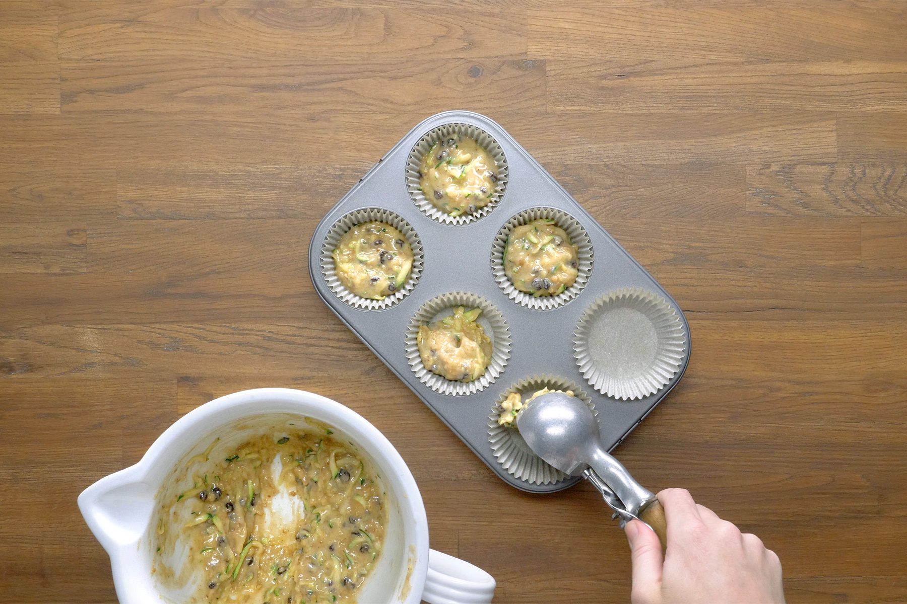 overhead shot; wooden background; Filling muffin cups three-fourths full with batter;