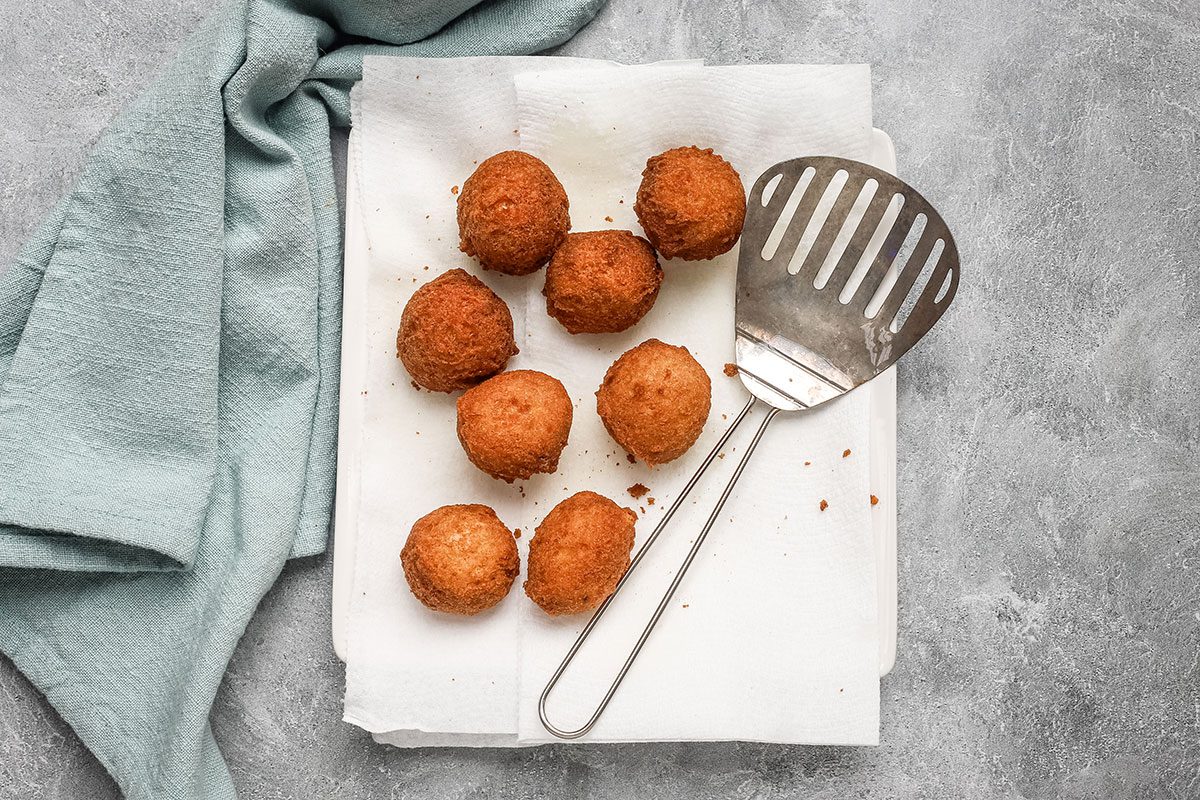 Fried banana beignets draining on paper towels.