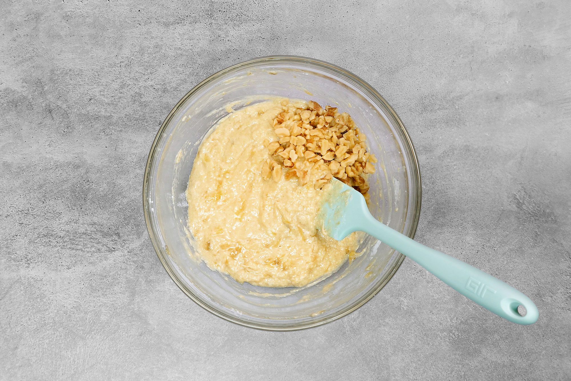 overhead shot; grey background; added walnuts into mixture in same bowl;