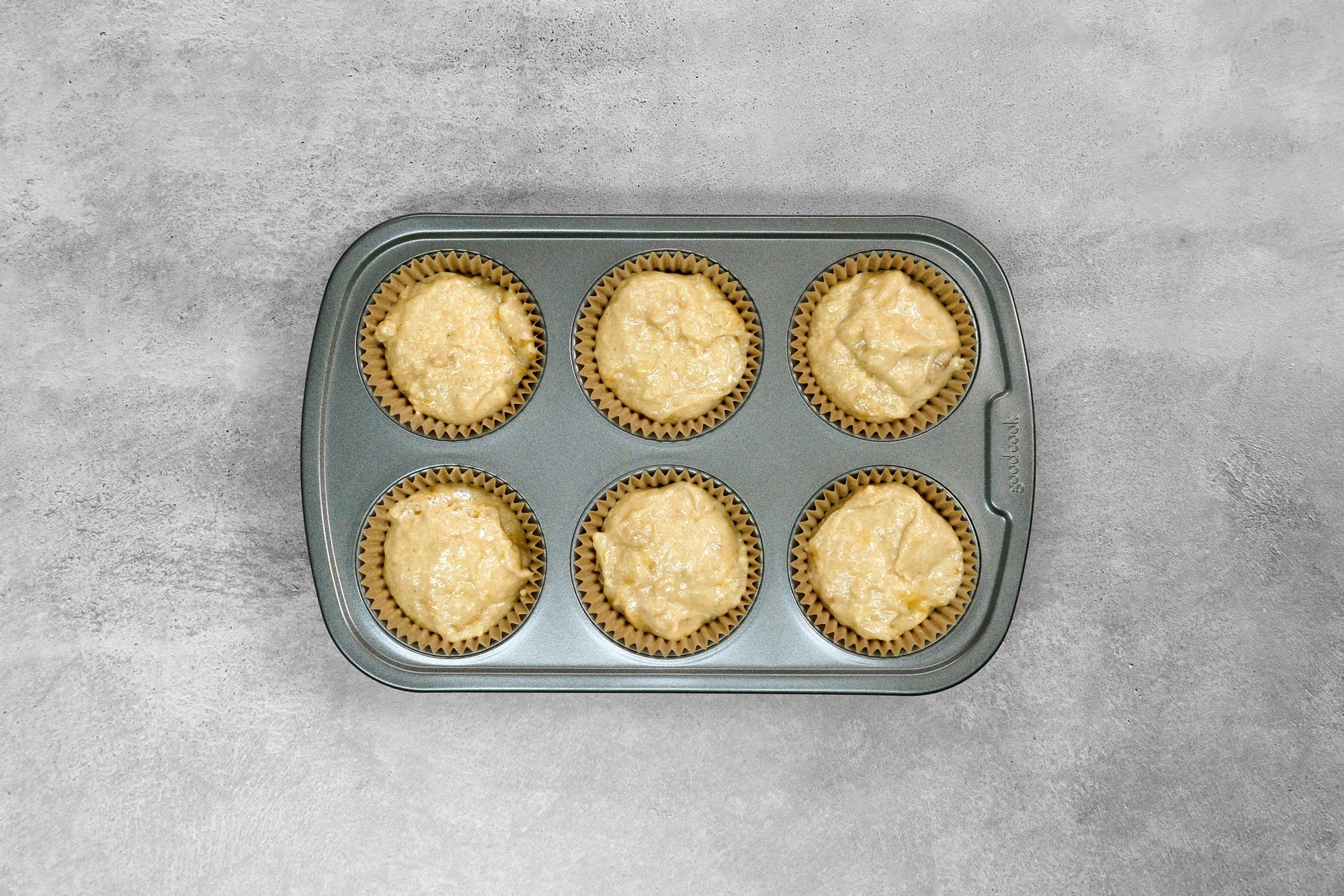 overhead shot; grey background; filled muffin cups two-thirds full with batter;