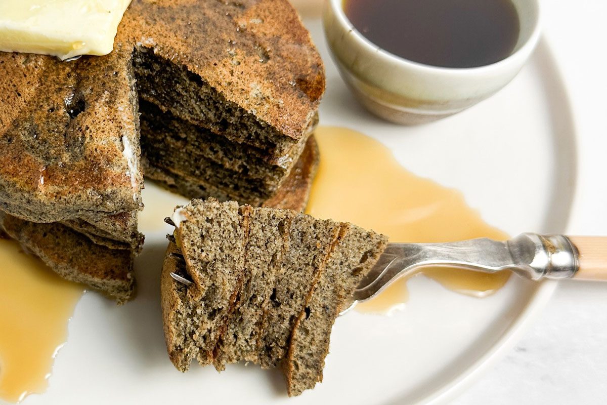 Taste of Home Buckwheat Pancakes with bacon and orange slices on a white plate