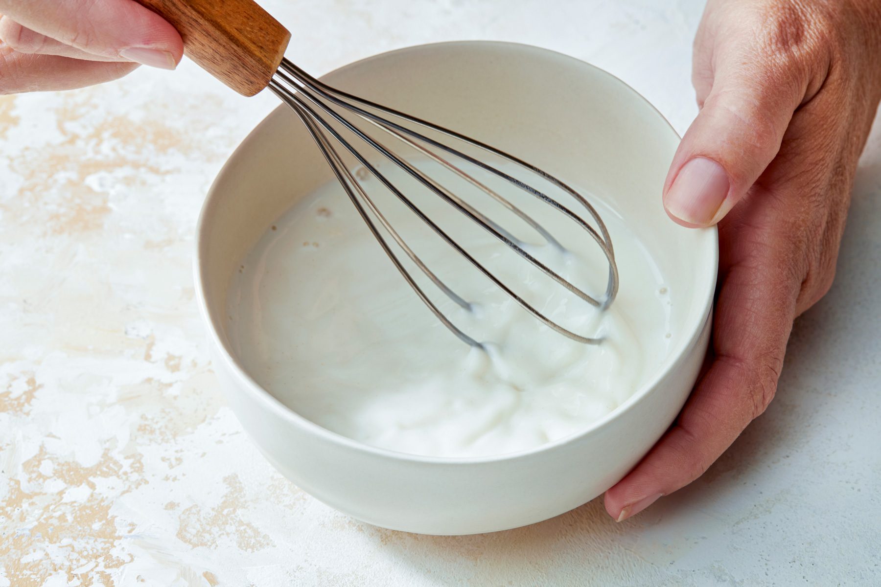 3/4th shot; white textured background; Whisking milk and flour mixture