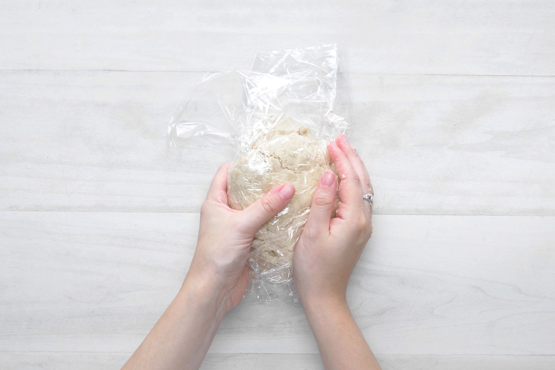 overhead shot; white wooden background; covered the dough with plastic wrap