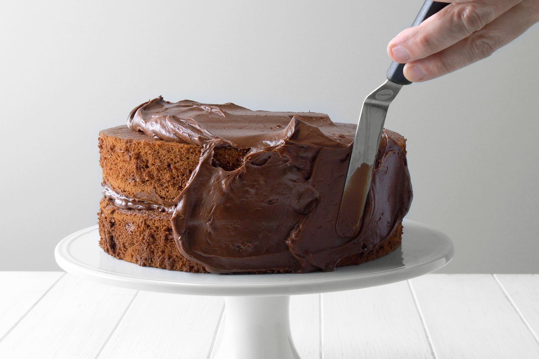 Frosting being applied to cake layers.