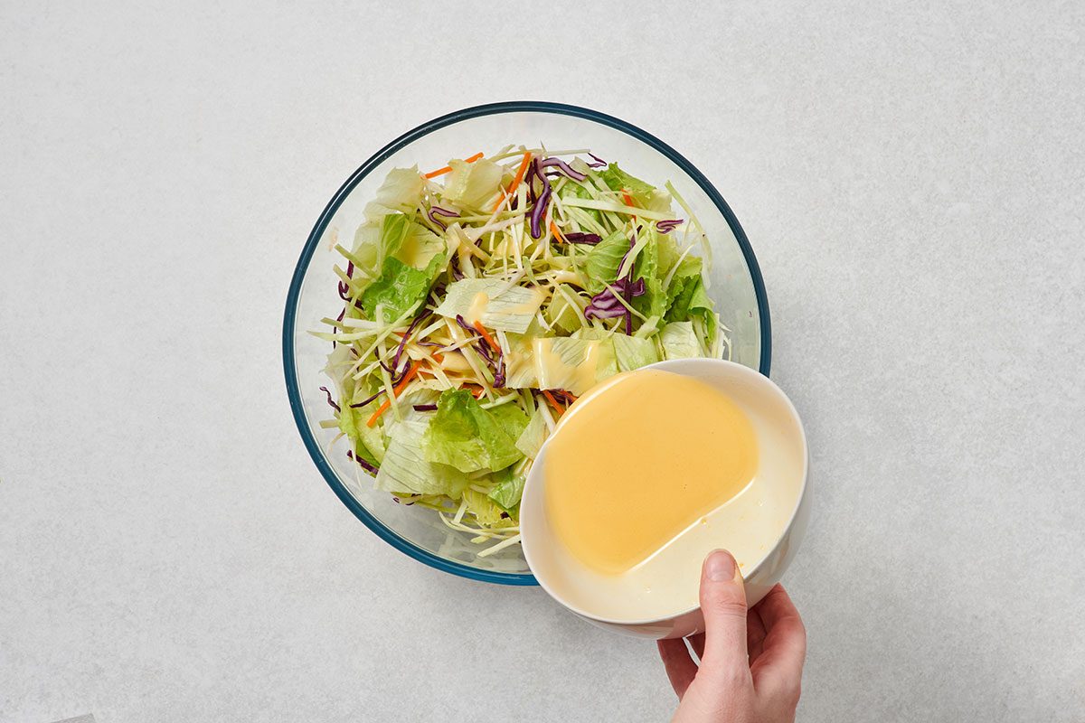 Pouring dressing over the mixed salad ingredients