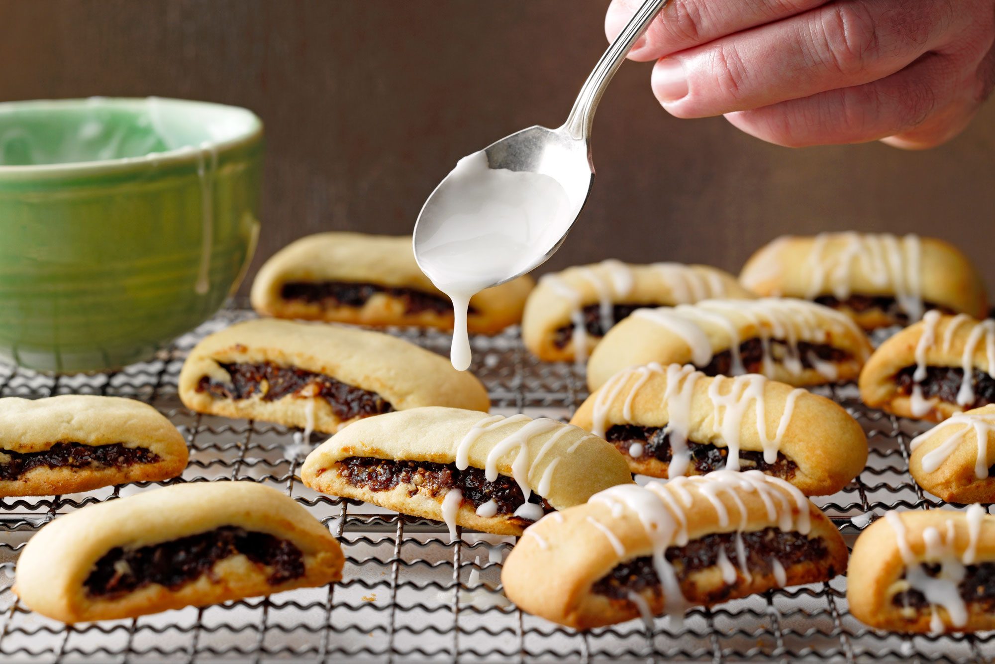 Cuccidati on cooling rack glazed with confectioners sugar and milk on top