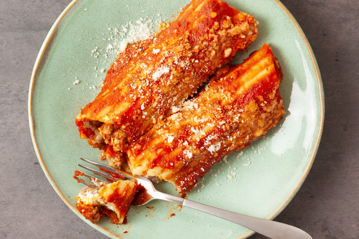 Close up of one serving of Taste of Home Meaty Manicotti on an aqua plate