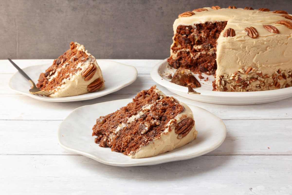 Full yield of Taste of Home Jam Cake on white wood surface with single servings, gold pie cake server