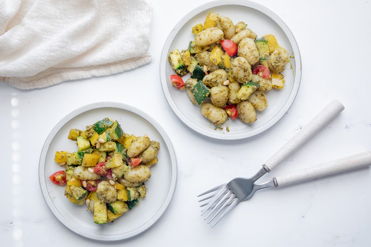 Overhead Beauty Shot for Taste of Home Pesto Gnocchi with two servings on plates on a marble surface.
