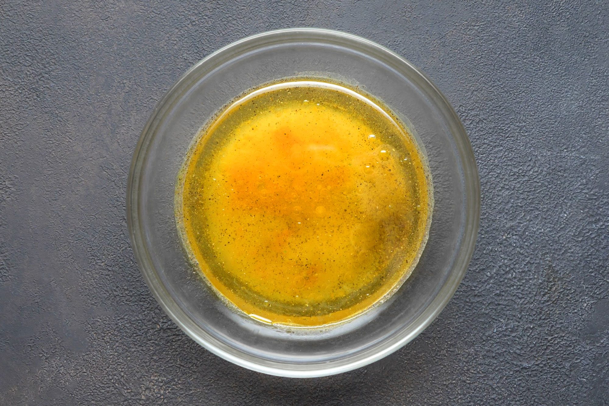 overhead shot; dark grey textured background; In a small bowl, whisked vinegar, sugar, pepper, contents of ramen seasoning packets and remaining oil;