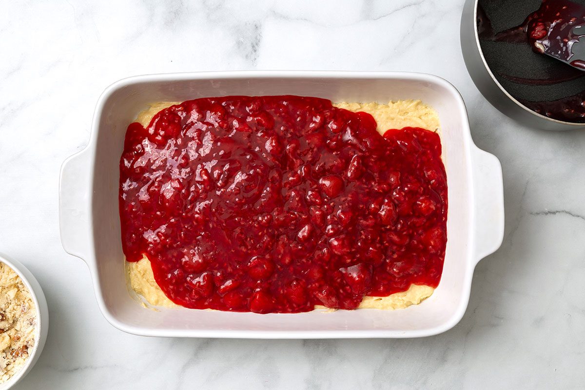 Batter in baking dish layered in with raspberry filling for step 3 of Raspberry Coffee Cake recipe for Taste of Home
