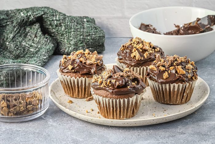 Peanut butter cup cupcakes frosted with a chopped peanut butter cup garnish.