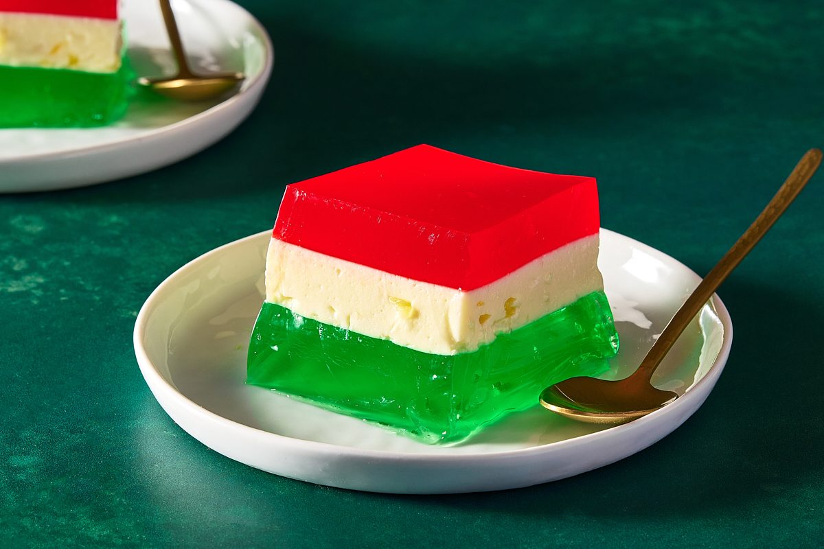 Two squares of ribbon jello served on small plates with spoons