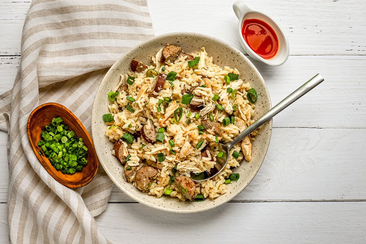 Taste of Home slow cooker chicken bog in a serving dish with green onions and hot sauce on the side.