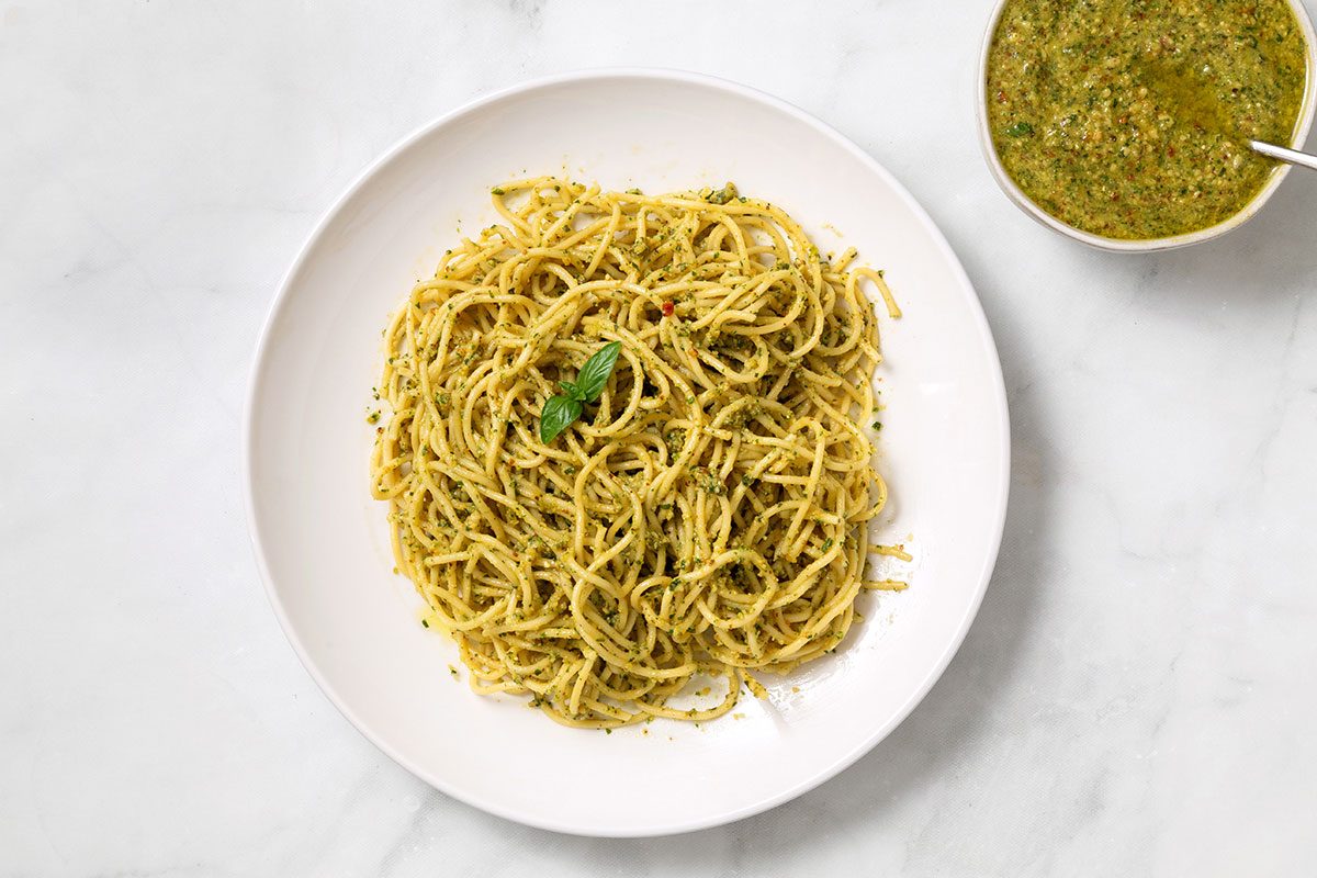 Homemade pesto sauce on plated spaghetti for step 2 of Spinach Pesto recipe for Taste of Home