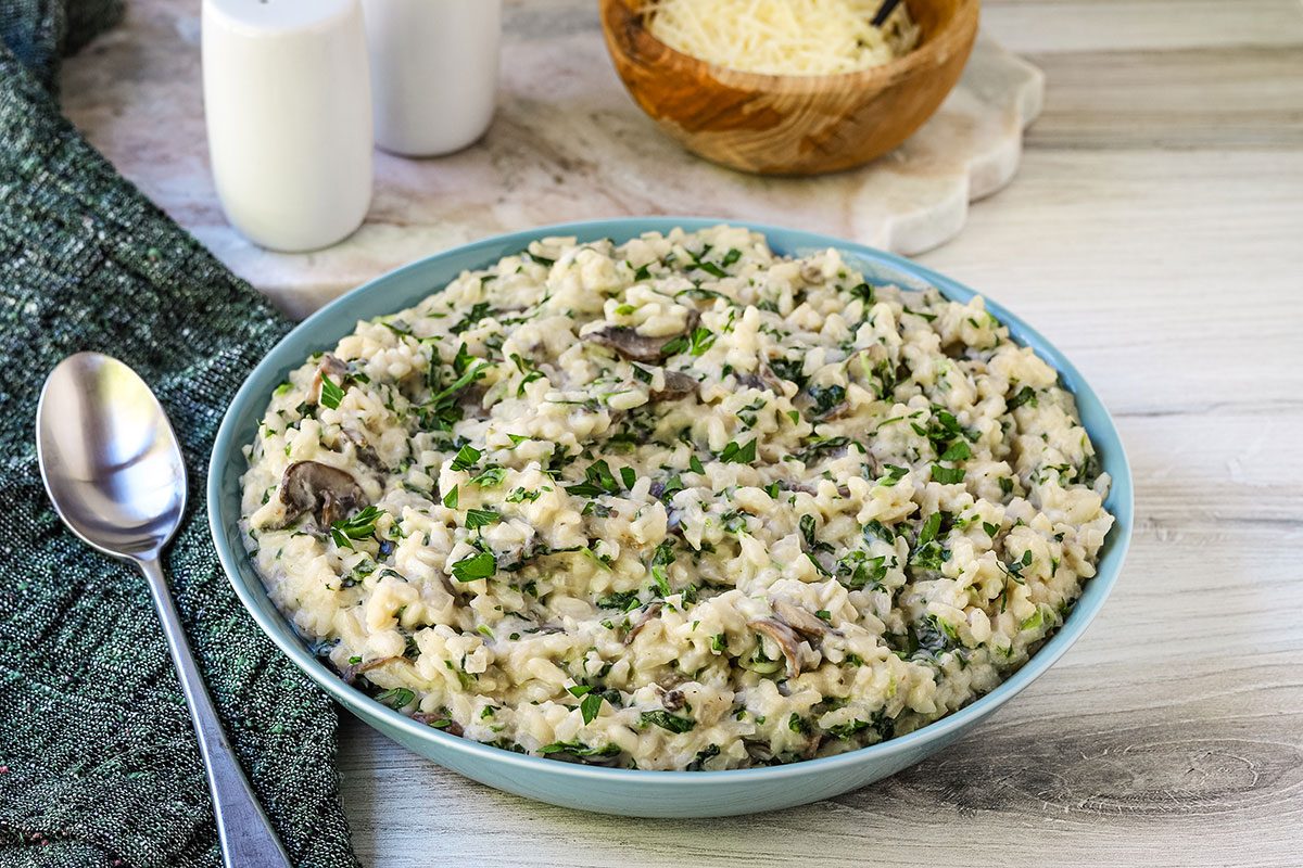 Creamy spinach risotto in a serving bowl with Parmesan alongside, from Taste of Home.