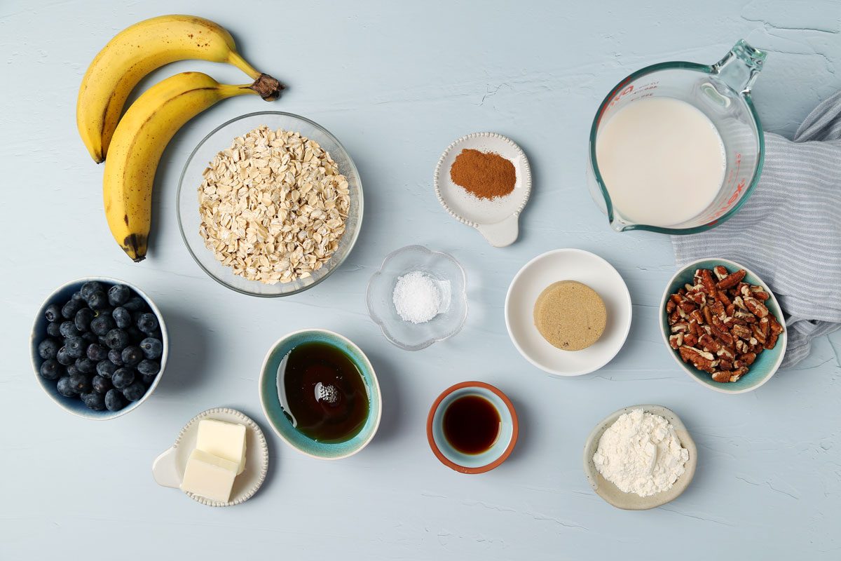 Ingredients for Taste of Home's Blueberry Baked Oatmeal in small dishes on a light blue surface.