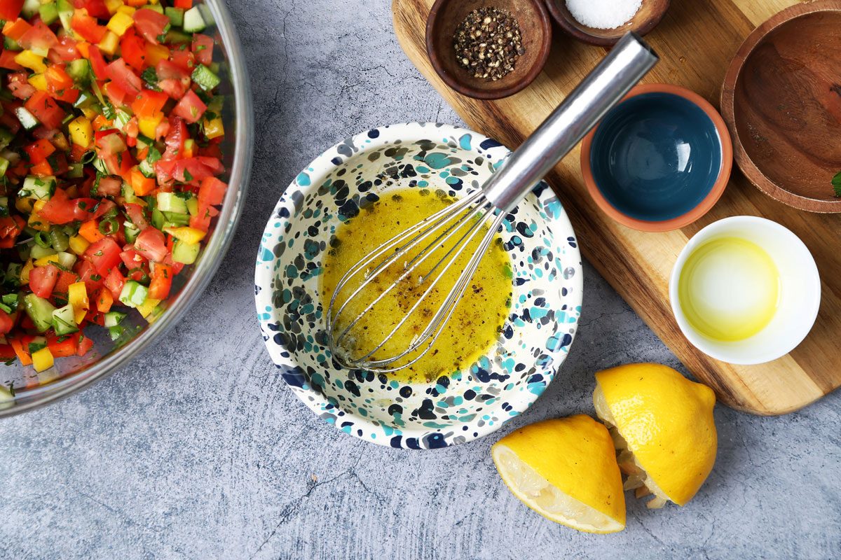 Process of making. Taste of Home's Israeli Salad in a large mixing bowl on a blue surface.