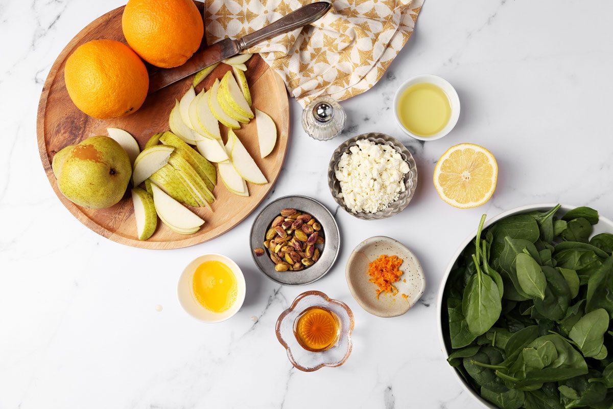 Ingredients for Taste of Home's Pear Salad on a white marble surface with a yellow linen.