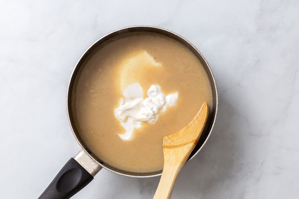 Sour cream added to white sauce mixture in saucepan